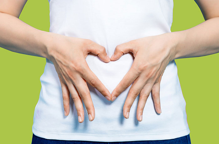 زنی که دستان خود را به شکل قلب روی شکم خود گرفته است. (به نشانه سلامت دستگاه گوارش)